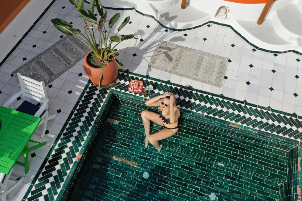 Casa De Nova Hotel في غومبيت: امرأة ترتدي البكيني جالسة في حمام السباحة