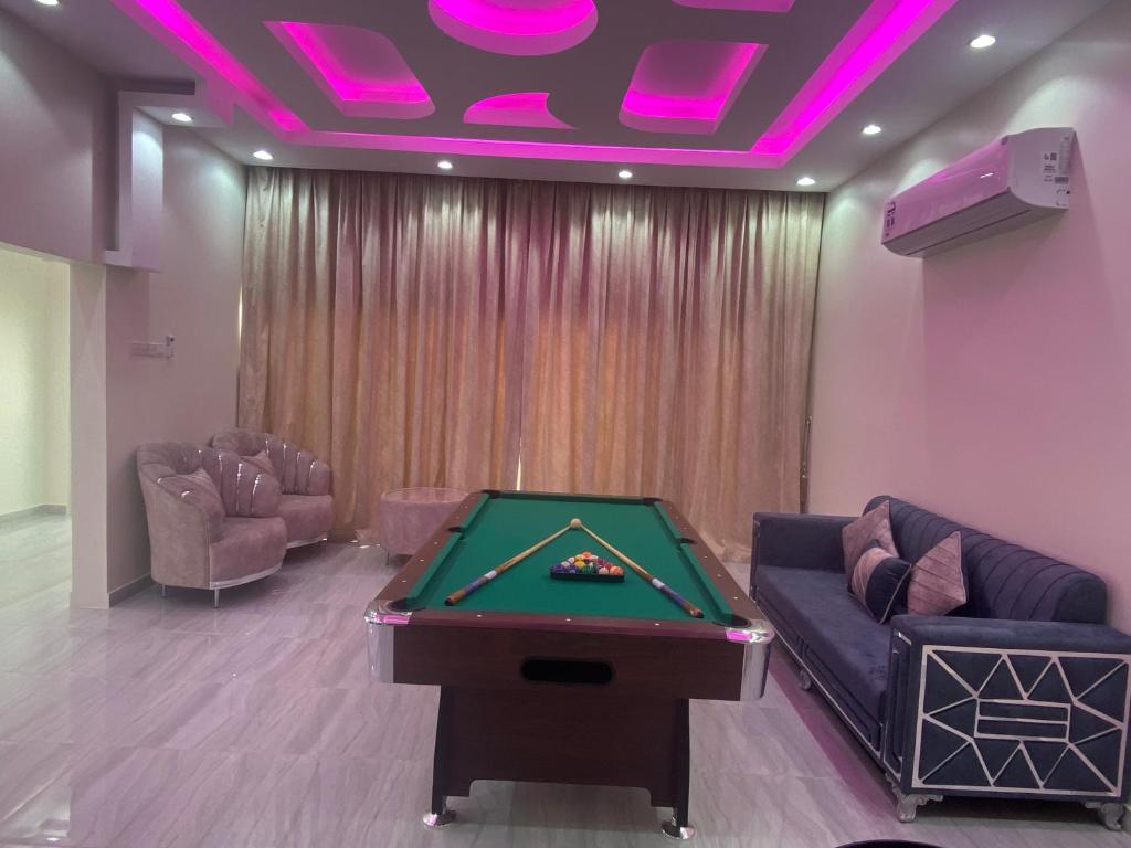 una sala de billar con mesa de billar e iluminación púrpura en شاليه درة رأس الجنز Dorrat Ras Al Jinz Chalet, en Junayz al Janūbī