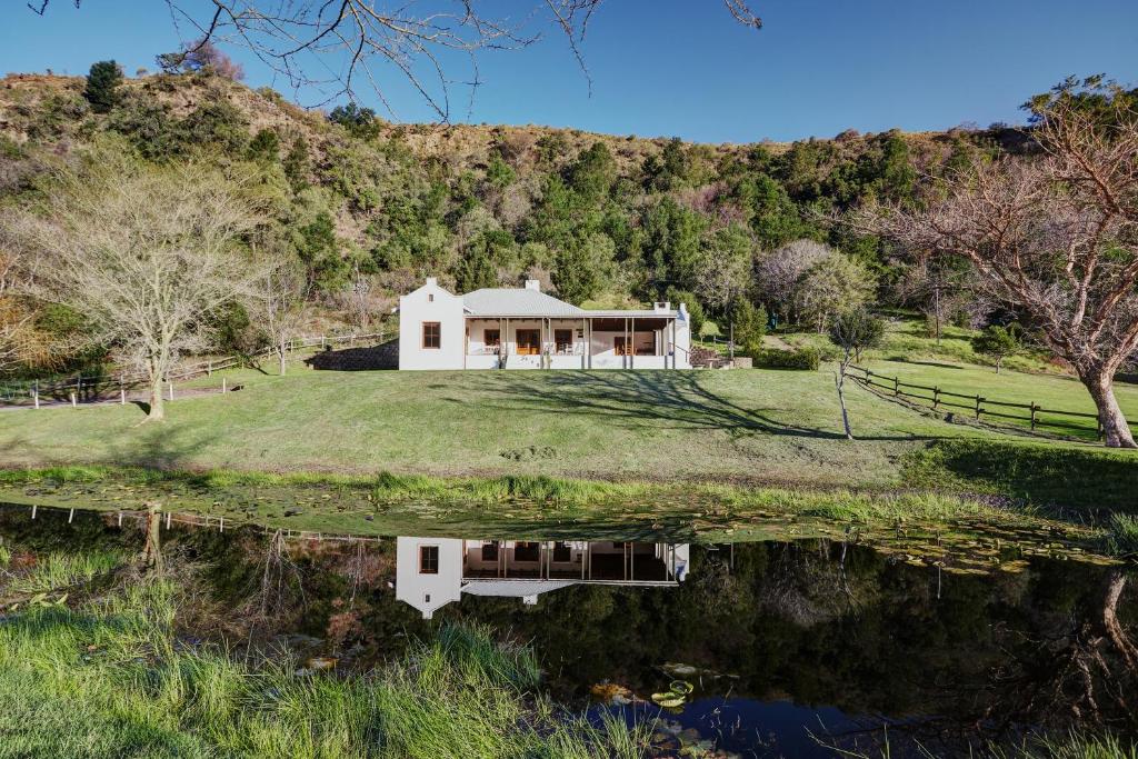 ein Haus auf einem Hügel mit einer Reflexion im Wasser in der Unterkunft Somerset Gift Getaway Farm in Swellendam