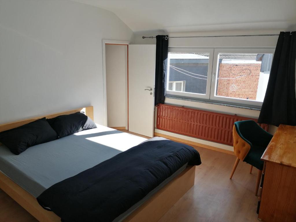 a bedroom with a bed and a desk and a window at Chambre cosy in Saint-Nicolas