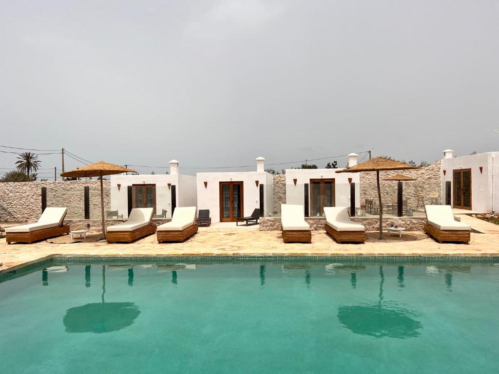a swimming pool with lounge chairs and a house at Villa Madame BABOUCHE - Maison Beldi avec piscine in Ghazoua