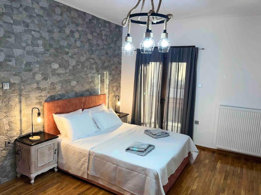 a bedroom with a large bed and a chandelier at Μιτάτο Οίτη in Pávliani