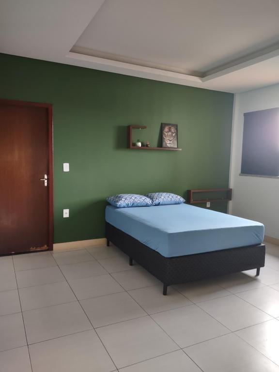 Un dormitorio con una cama azul y una pared verde en Residencial Isaura, en Rio Branco