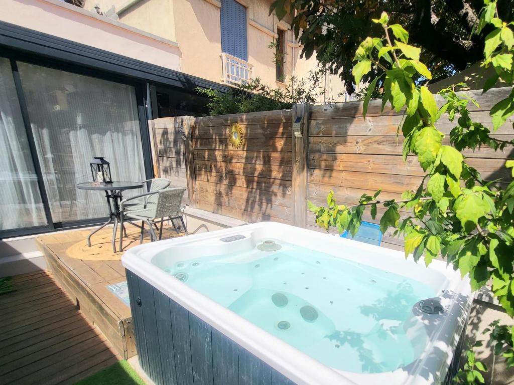 eine Whirlpool-Badewanne auf einer Terrasse mit einem Tisch in der Unterkunft Villa-nova avec spa à 5 minutes des remparts. in Avignon