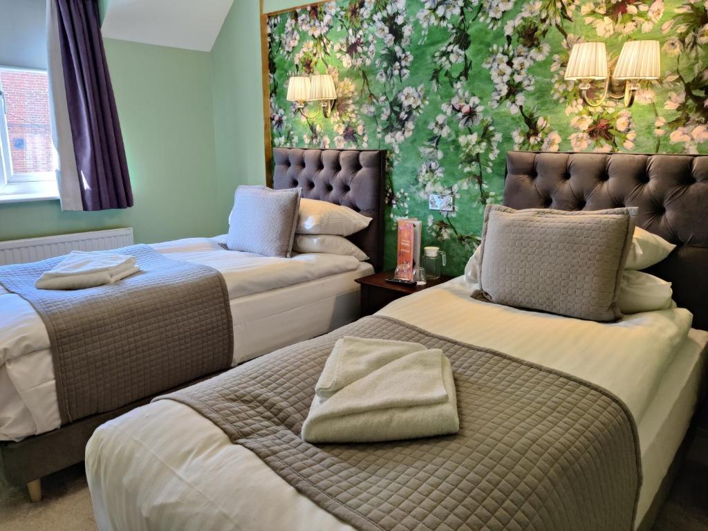 two beds in a room with a floral wall at The Bingham Townhouse in Bingham