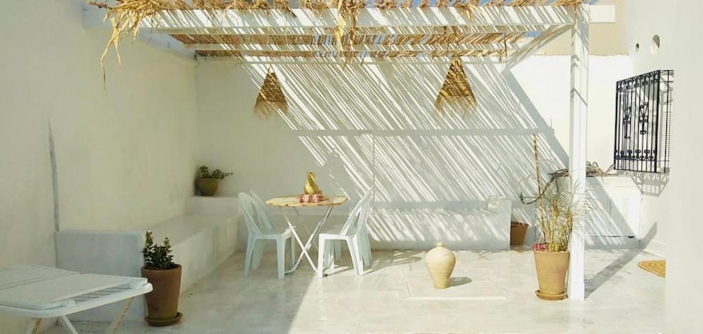 Dar almasyaf, maison bord de mer في Gabès: غرفة بيضاء فيها طاولة وكراسي