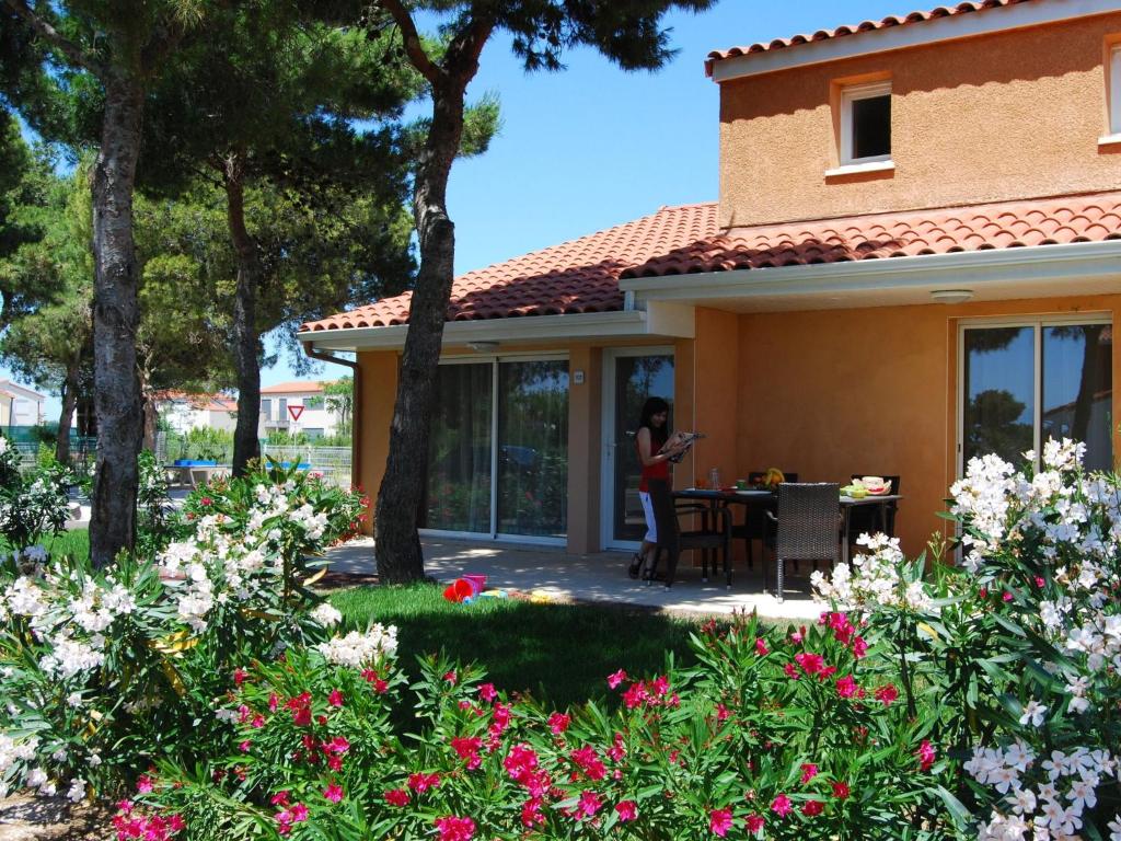 une femme debout à l'extérieur d'une maison avec des fleurs dans l'établissement Holiday Home in France with Garden Terrace, à Torreilles