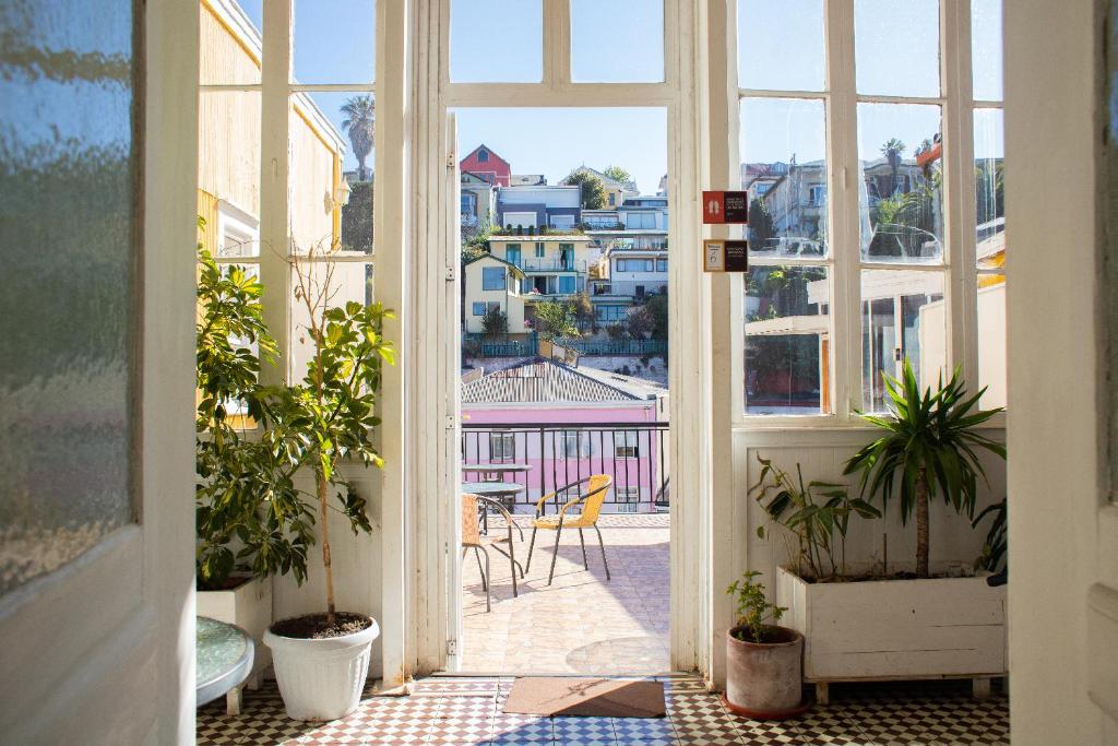 Une porte ouverte s'ouvre sur un balcon orné de plantes en pot. dans l'établissement La Galería B&B, à Valparaíso