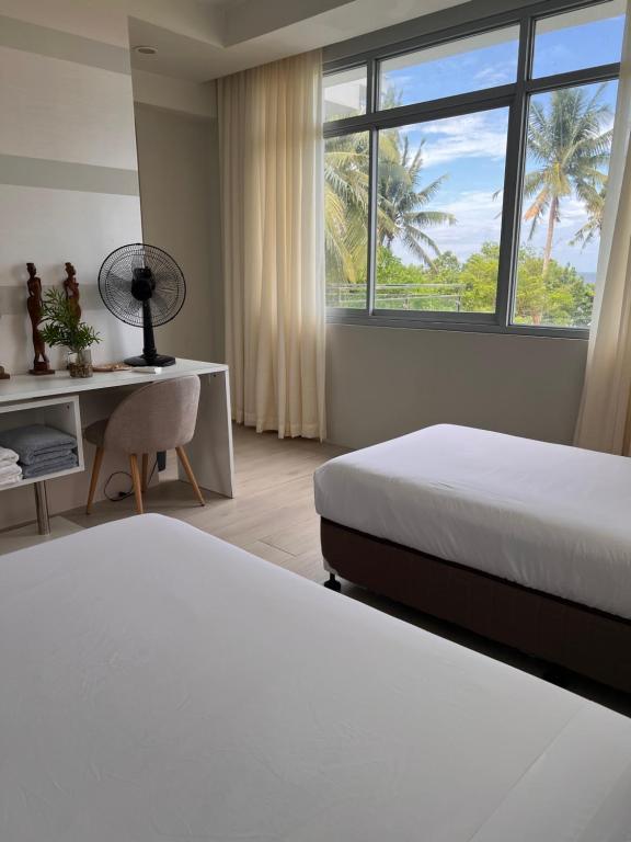a bedroom with two beds and a desk and a window at D ARC Leisure Home By The Sea in Panglao
