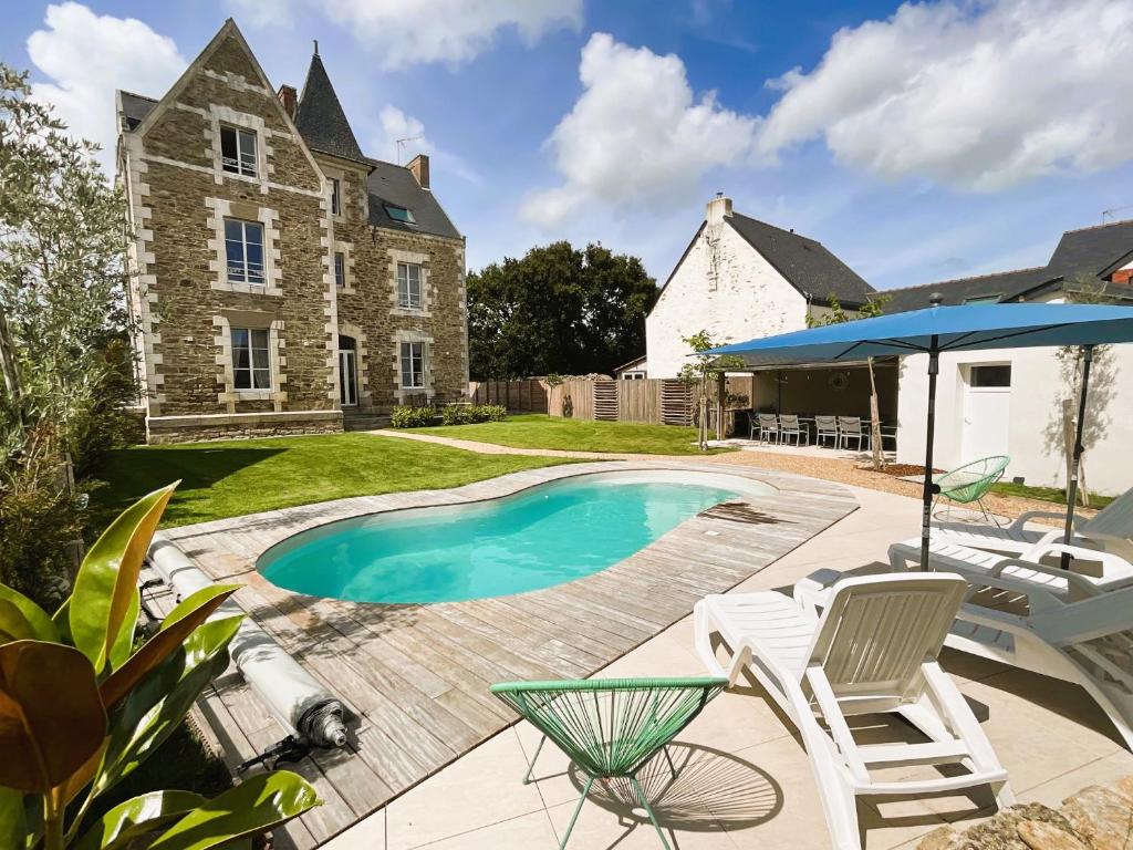 een achtertuin met een zwembad en stoelen en een huis bij Manoir de la Fontaine Saint-Jean in Crossac