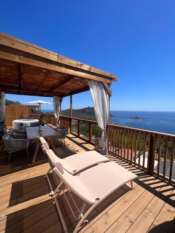 una terraza con mesa, sillas y el océano en Mobile home grand confort 3 chambres neuf en Saint-Raphaël