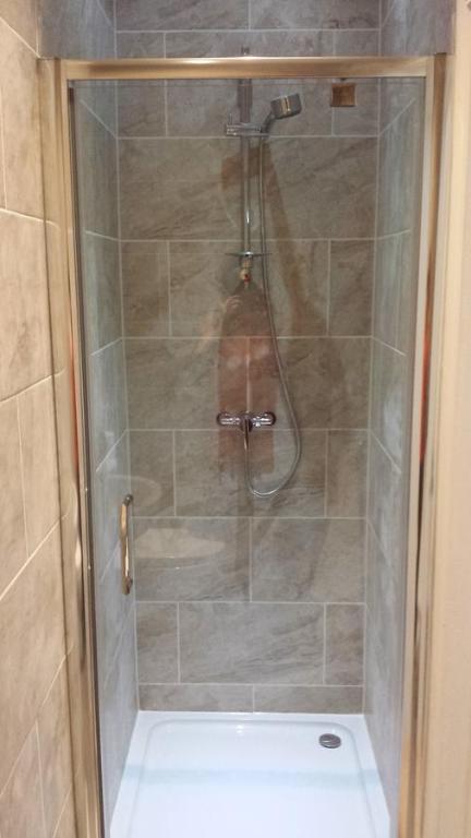 a shower with a glass door in a bathroom at The Railway Inn Westerfield in Ipswich