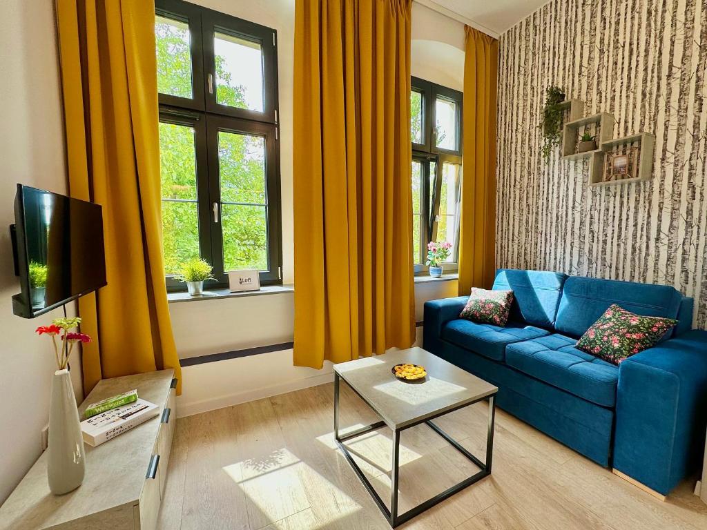 a living room with a blue couch and a window at Loft Apartments Gliwice in Gliwice