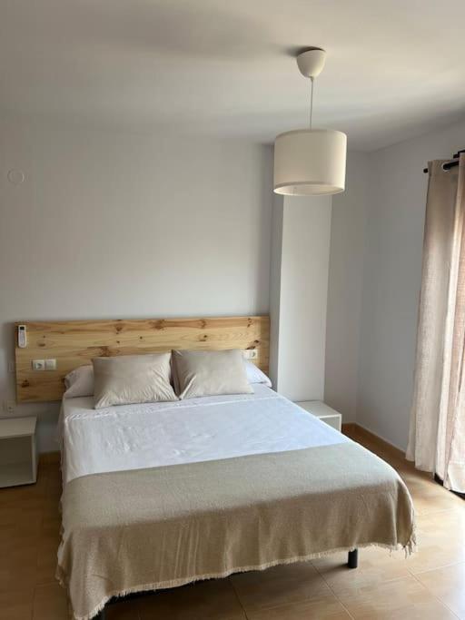 1 dormitorio con 1 cama blanca grande y cabecero de madera en Rincón Costero, en Rincón de la Victoria