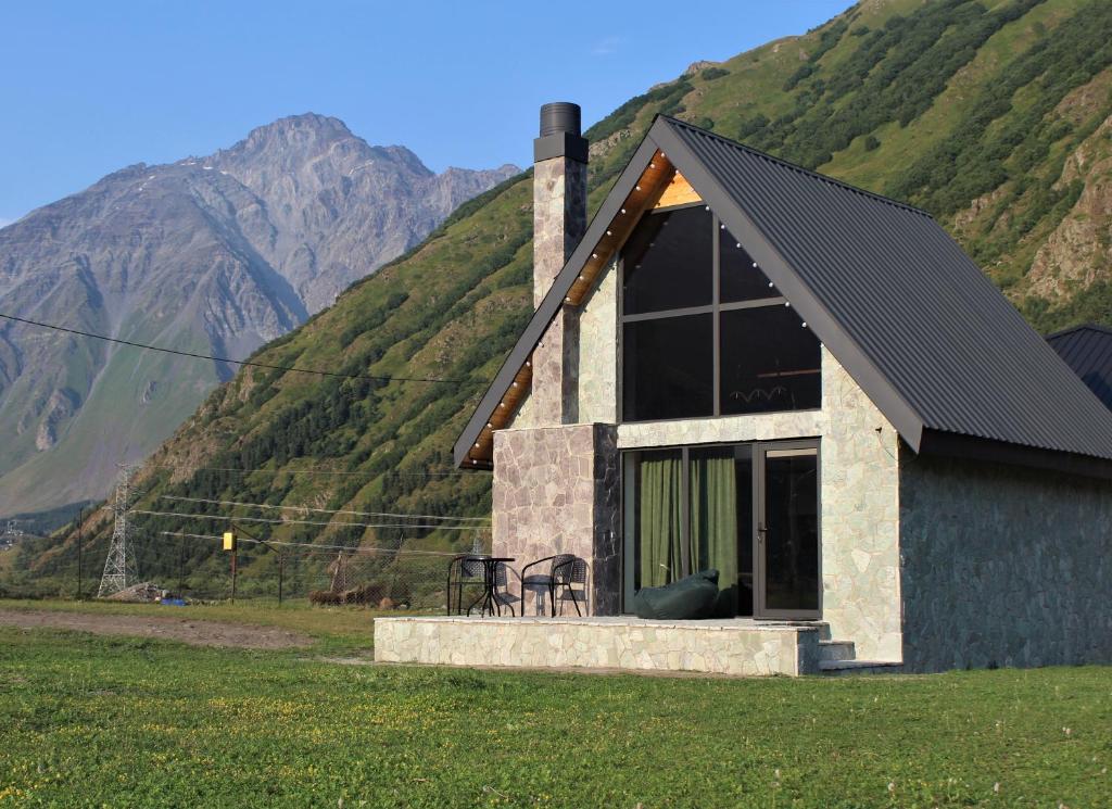 a house in a field with mountains in the background at Cottage Milo Kazbegi in Stepantsminda