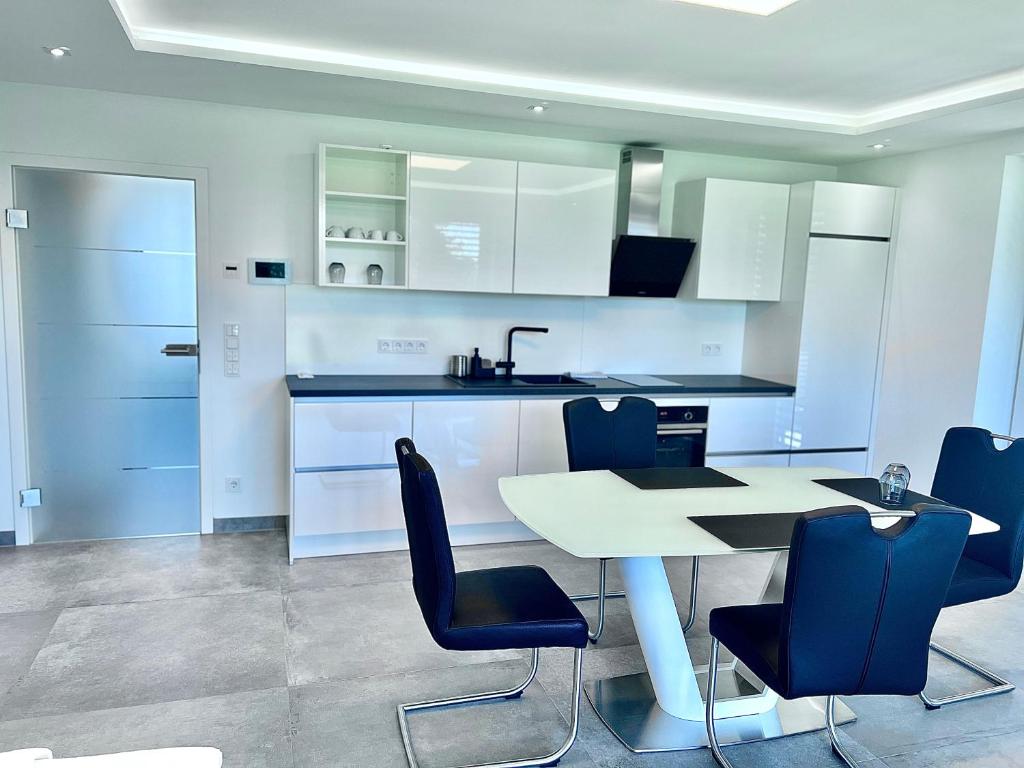 a kitchen with a white table and blue chairs at City Apartments in Herzogenaurach