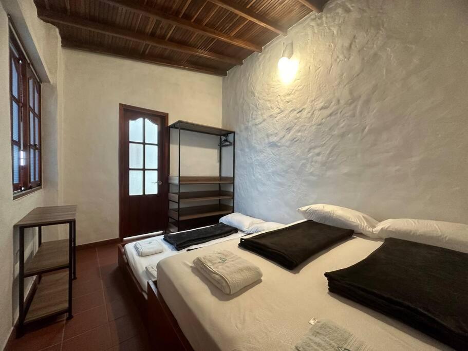 1 dormitorio con 1 cama con sábanas blancas y ventana en Casa Victoria, en Zapatoca