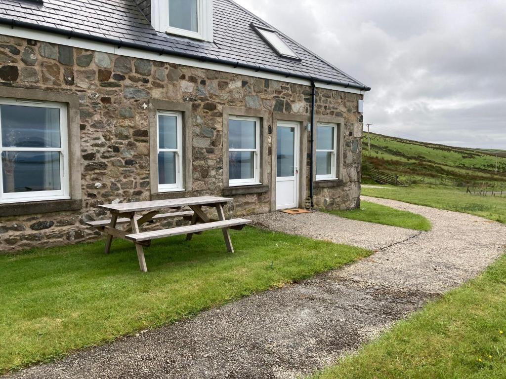 a picnic table in front of a stone house at Honeysuckle Cottage in Killean