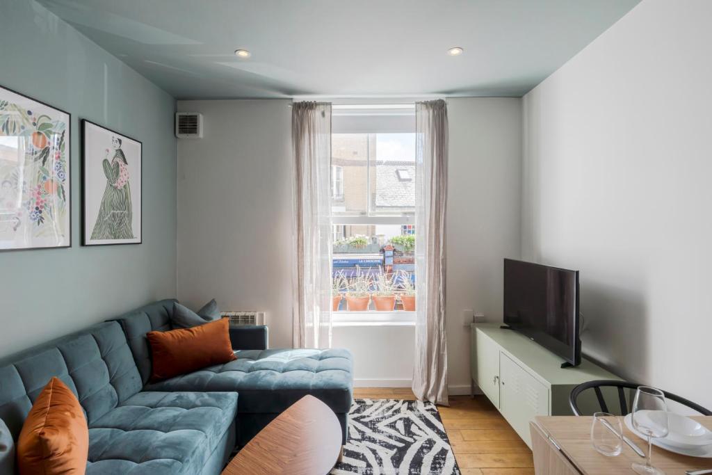 a living room with a blue couch and a window at Bijou flat on Broadway Market in London