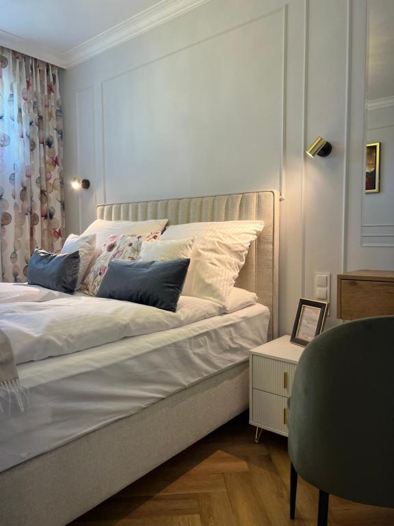 ein Schlafzimmer mit einem weißen Bett mit Kissen darauf in der Unterkunft Bella Casa Luxury Apartament in Radom