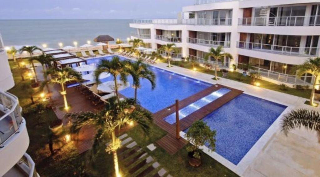 Cet hôtel possède une piscine et des palmiers en face de l'océan. dans l'établissement Dunas de Cotovelo, à Parnamirim