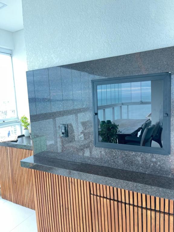 un reflejo de una silla en un espejo en una pared en COBERTURA com belíssima vista para o mar e jacuzzi, en Itapema