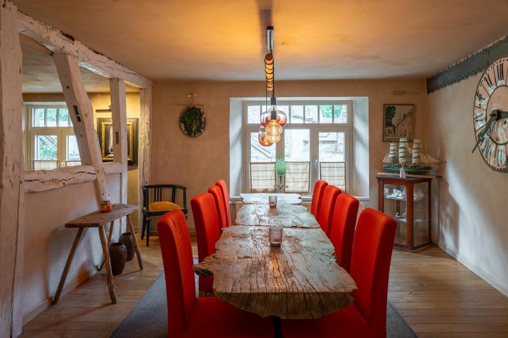 a dining room with a long table and red chairs at Le Nid de la Canette in Durbuy