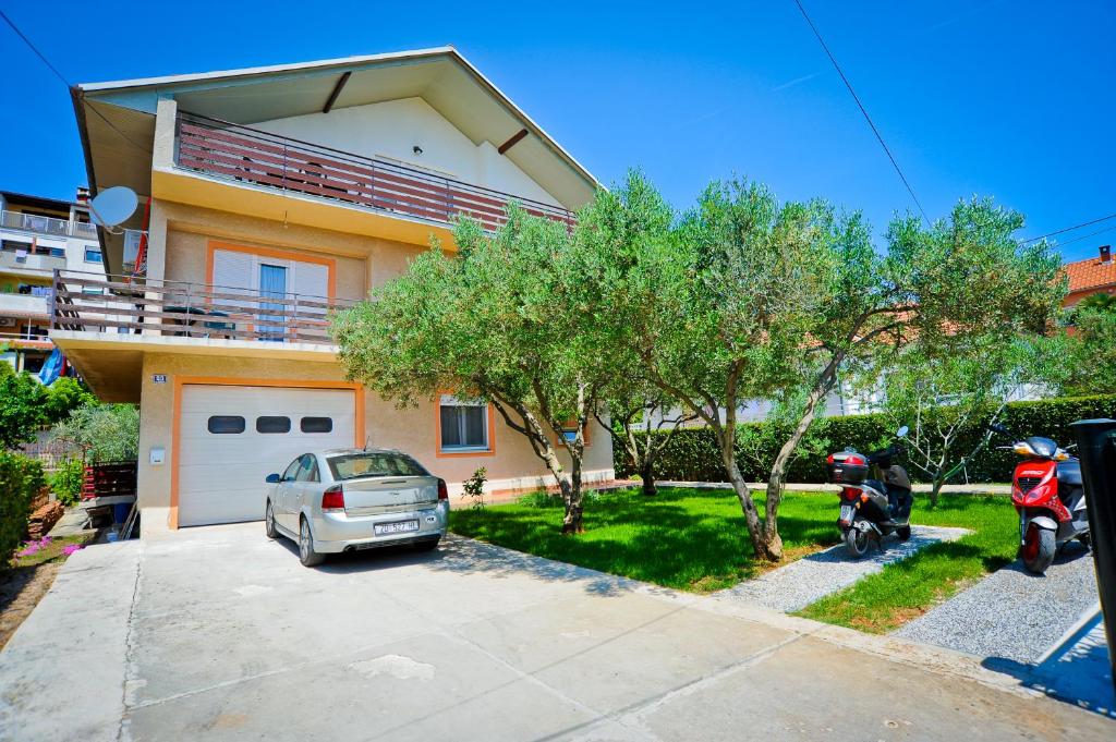 a house with a car parked in a driveway at Apartmani Roko in Zadar