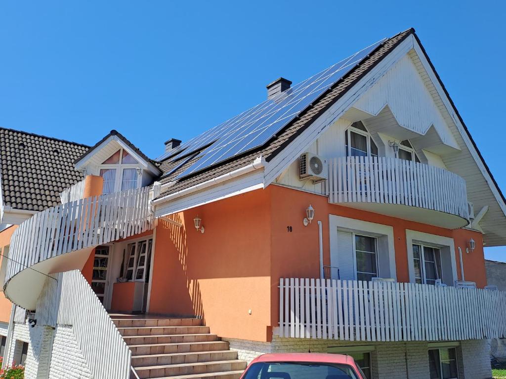 una casa naranja con techo solar en Alinka Apartmanház, en Balatonlelle