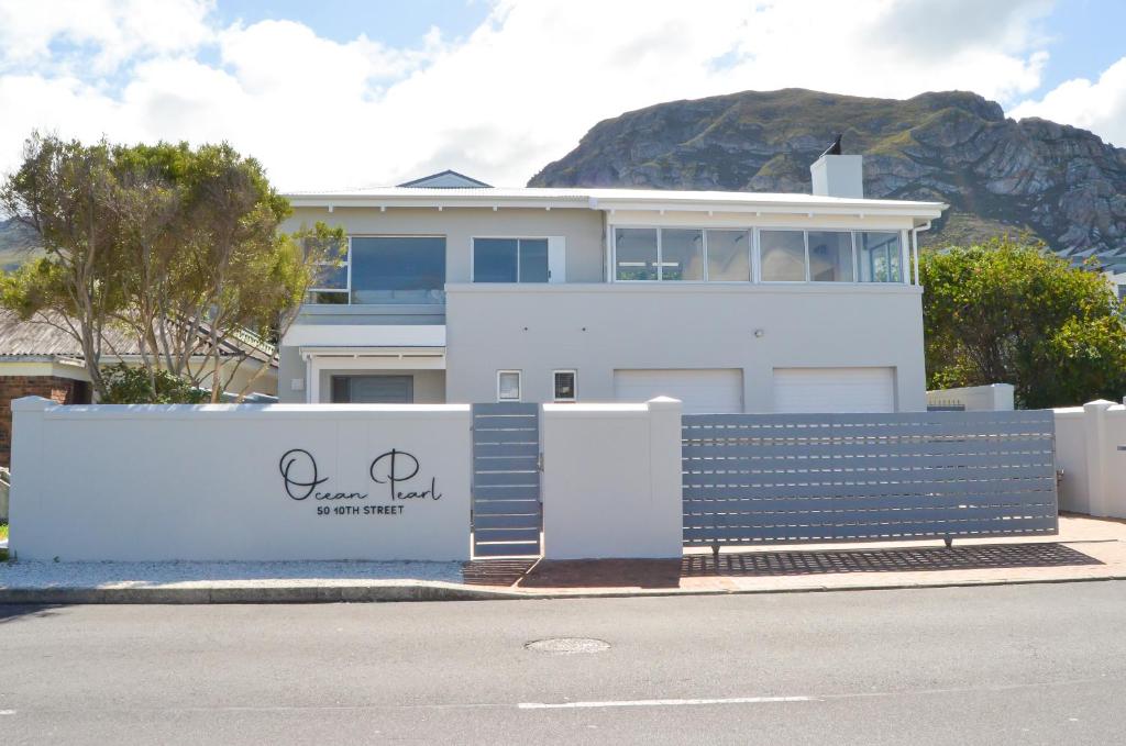 uma casa branca com uma cerca à frente. em Ocean Pearl Hermanus - 5 Bedrooms em Hermanus