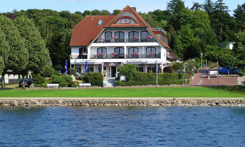 a large white house sitting next to a body of water at Hotel Seerose Bad Malente in Malente