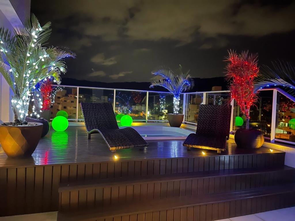 a rooftop deck with chairs and palm trees at night at Mariscal Praia Centro Vista al Mar Departamento de Lujo in Canto Grande