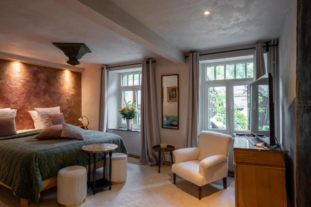 een slaapkamer met een bed, een stoel en ramen bij Le Poirier de la Canette in Durbuy