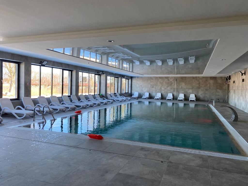 ein Pool mit weißen Stühlen und einem Pool- in der Unterkunft Red bridge Resort - Apartament & SPA in Dziwnów