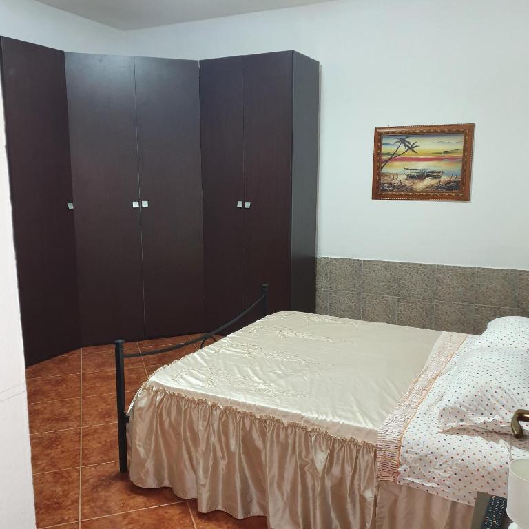 a bedroom with a bed and some brown cabinets at b e b bascus argius in Cagliari