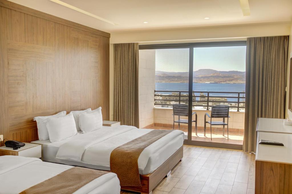 a hotel room with two beds and a balcony at Luciana Hotel by BRATUS in Aqaba