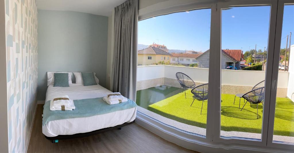 a bedroom with a bed and a balcony with a view at Apartamentos TARELA Porriño in Porriño