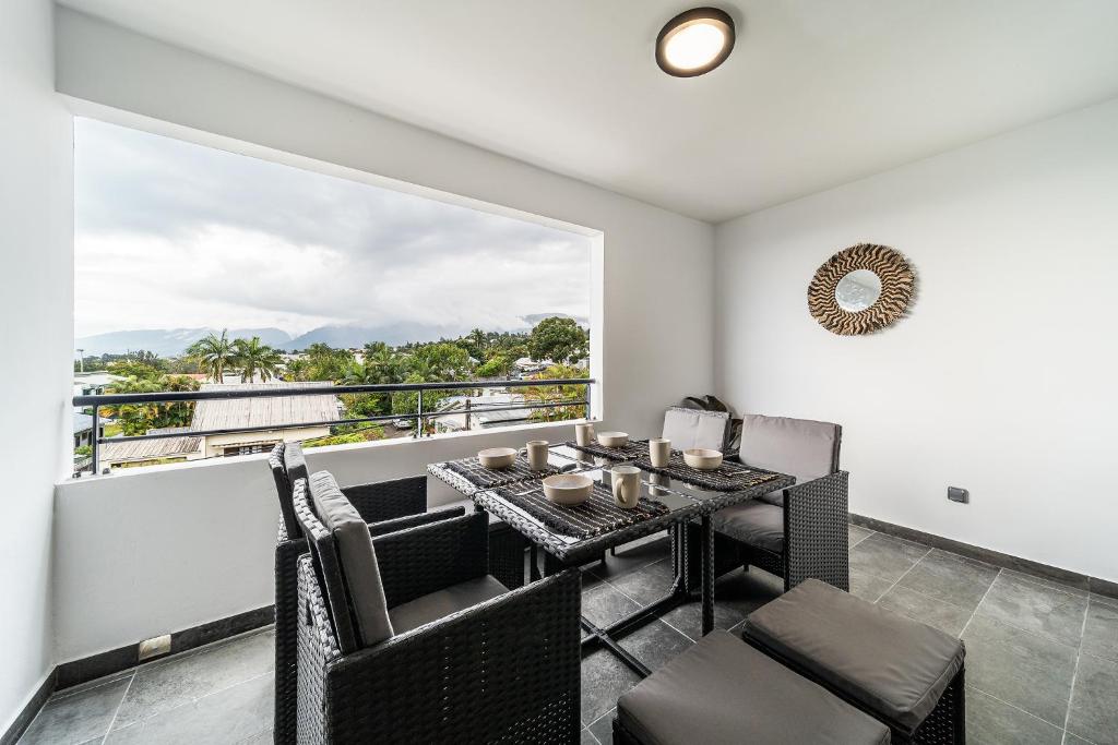 a dining room with a table and chairs and a large window at Appartement spacieux avec vue in Le Tampon