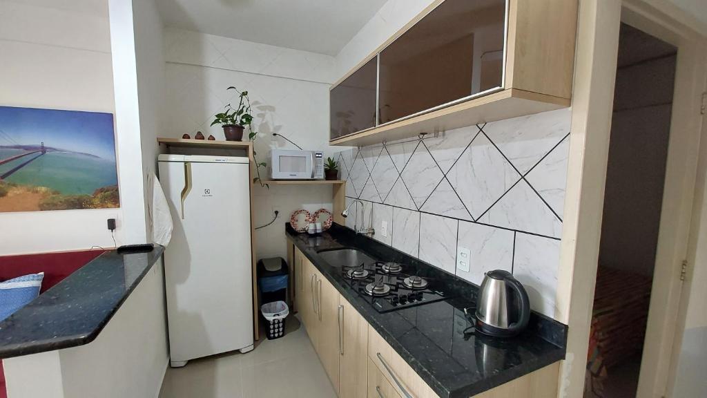 Il comprend une petite cuisine équipée d'une cuisinière et d'un réfrigérateur. dans l'établissement Apto 2 Quartos com Ar a 200m da Praia, à Florianópolis