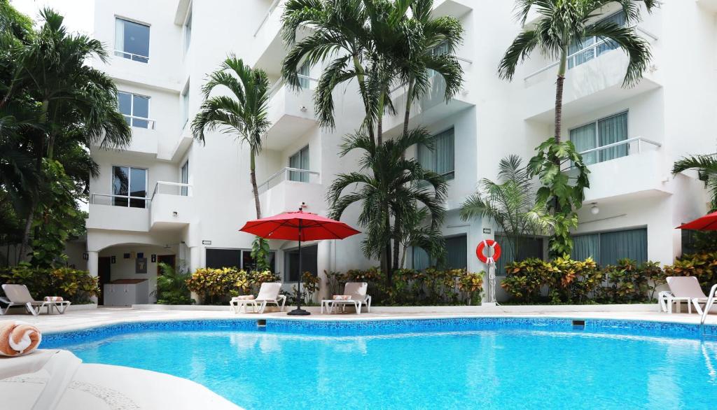 una piscina frente a un hotel con palmeras en Adhara Express, en Cancún