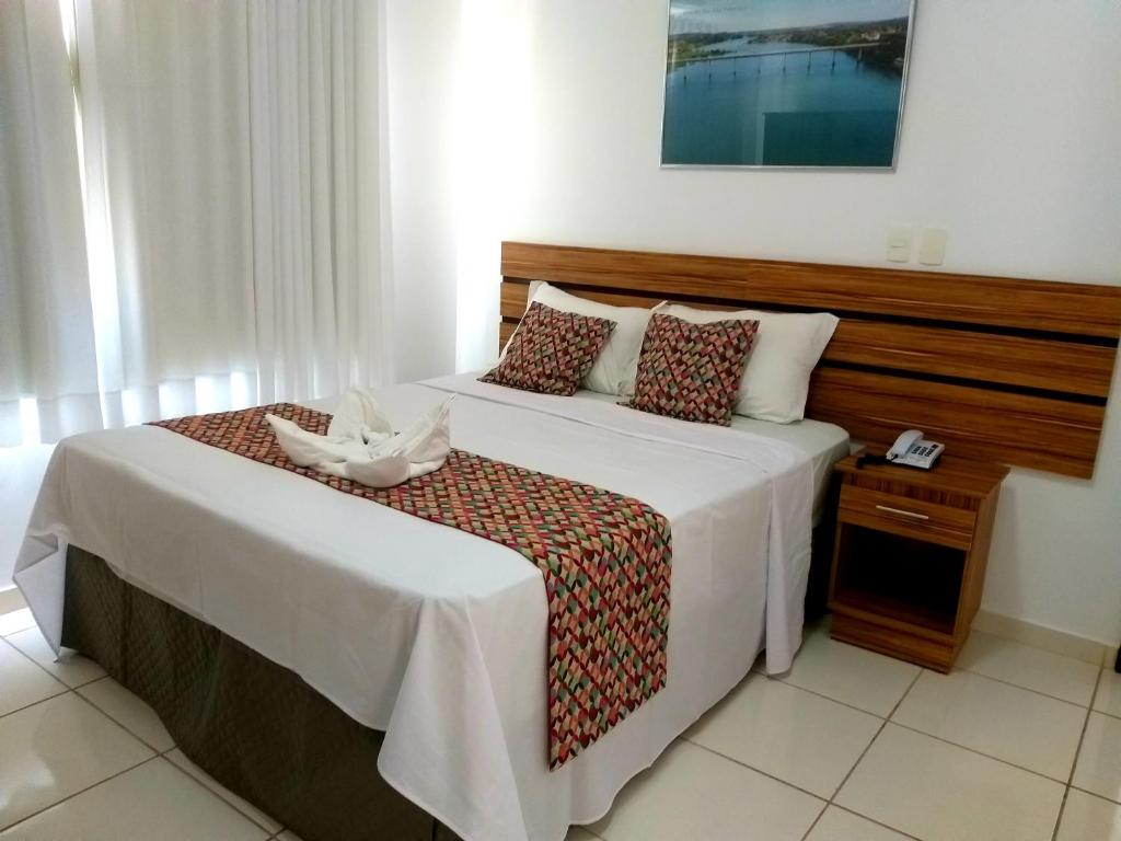 a bedroom with a large bed with a wooden headboard at Hotel Estrela Mares in Três Marias