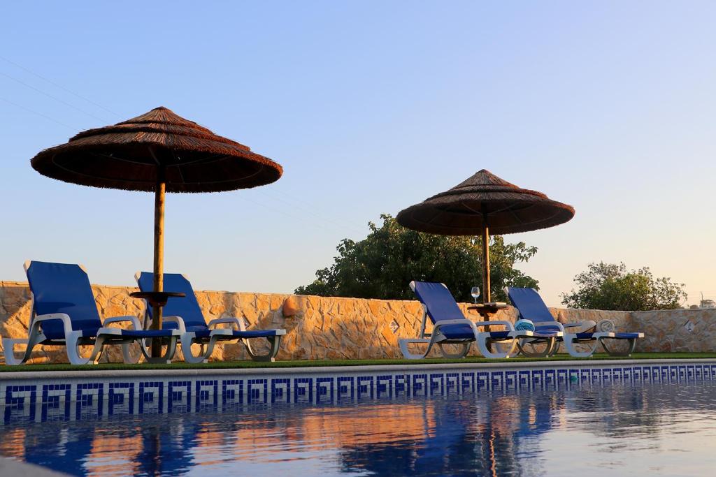 un grupo de sillas y sombrillas junto a una piscina en Quinta Ribeirinha - Lagos, en Bensafrim