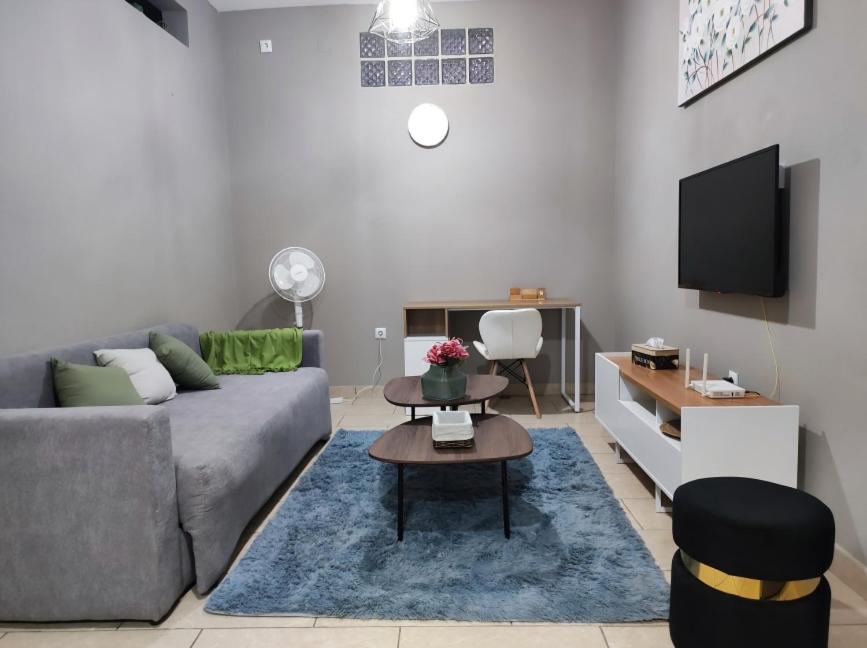 a living room with a gray couch and a tv at Chonguile Villa 1 Modern Minimalist in Matola in Matola