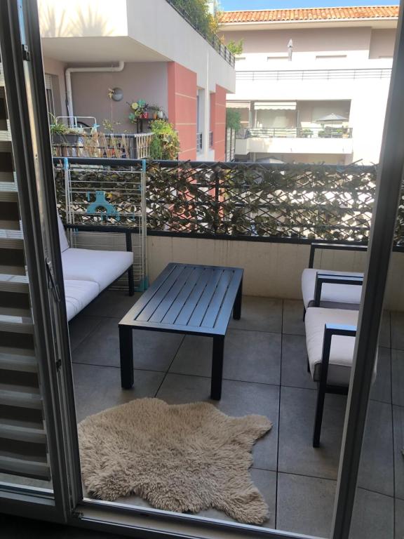 einen Teppich auf einem Balkon mit einer Bank und einem Tisch in der Unterkunft Large studio with private parking Vallauris in Vallauris