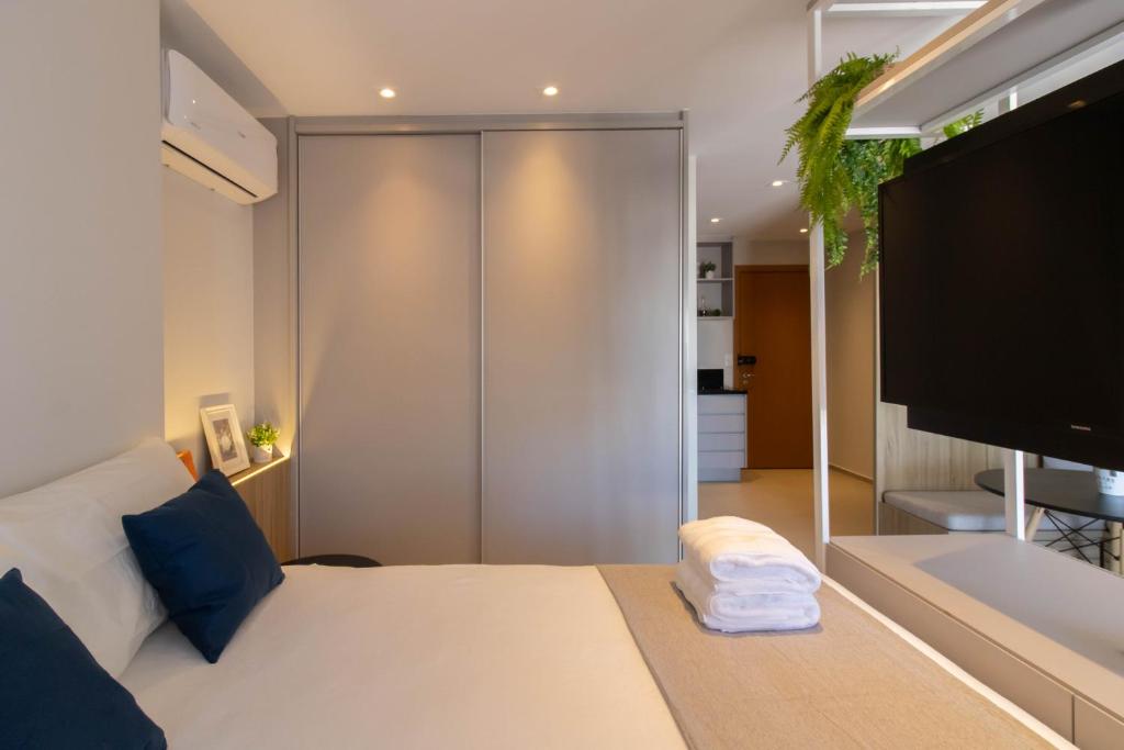 1 dormitorio con 1 cama blanca y TV grande en Avenue Studio - GRU, en Guarulhos