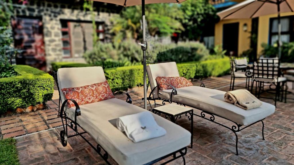 two chairs and an umbrella on a patio at Hacienda de las Flores in San Miguel de Allende