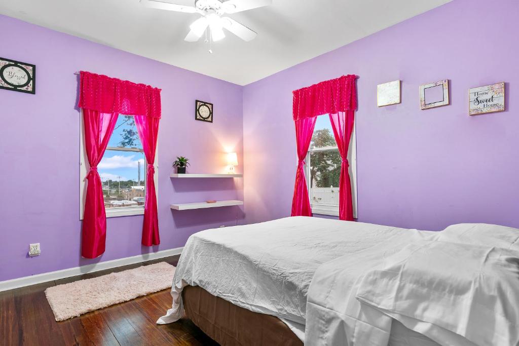 Schlafzimmer mit lila Wänden und einem Bett mit roten Vorhängen in der Unterkunft The Pink Room near Yale Hospital/Bridegport in Bridgeport