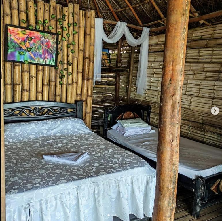 a bedroom with two beds in a log cabin at Hostal Paraíso in Guachaca