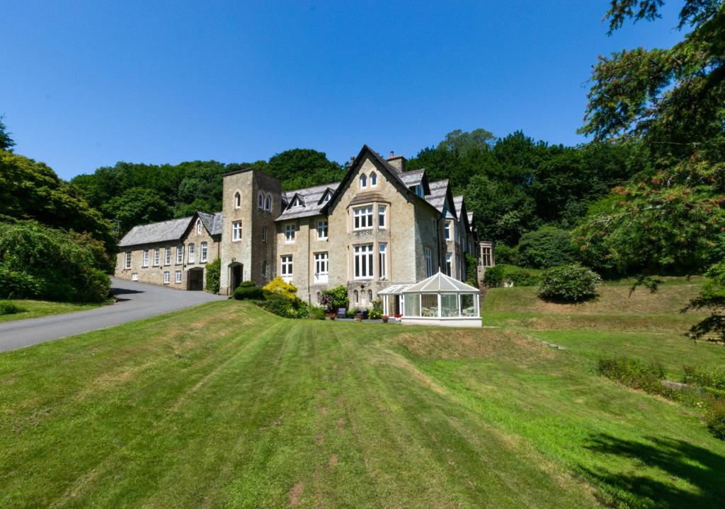 une grande maison sur une colline avec un champ verdoyant dans l'établissement The Retreat, à Blackawton