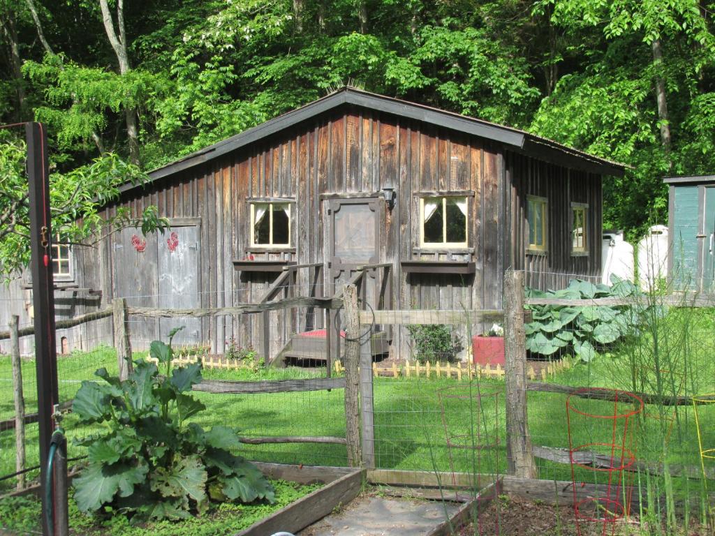 an old wooden shed in a yard with a fence at The Renovated Barn at Seneca Rocks in Seneca Rocks